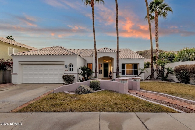 mediterranean / spanish house with a garage and a lawn