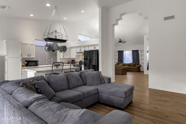 living room with a wealth of natural light, ceiling fan, a towering ceiling, and dark hardwood / wood-style floors