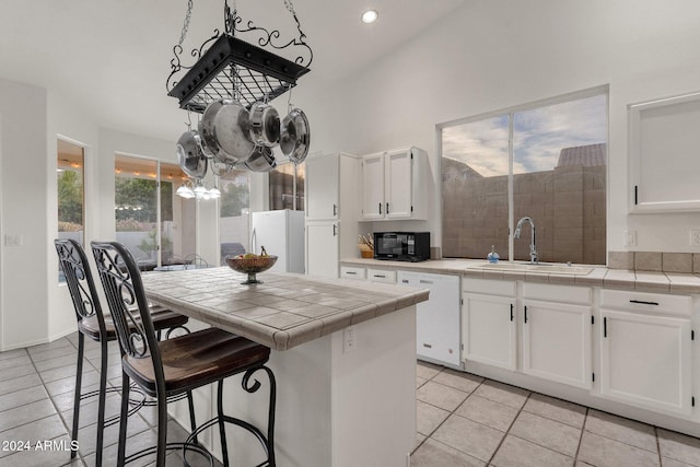 kitchen with white cabinetry, sink, tile countertops, white appliances, and light tile patterned flooring