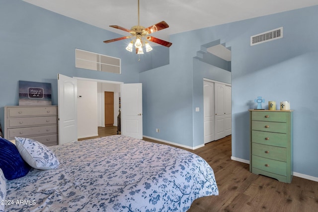 bedroom with a towering ceiling, dark hardwood / wood-style flooring, a closet, and ceiling fan