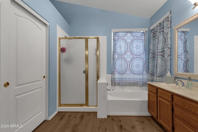 bathroom with vanity, hardwood / wood-style flooring, independent shower and bath, and lofted ceiling