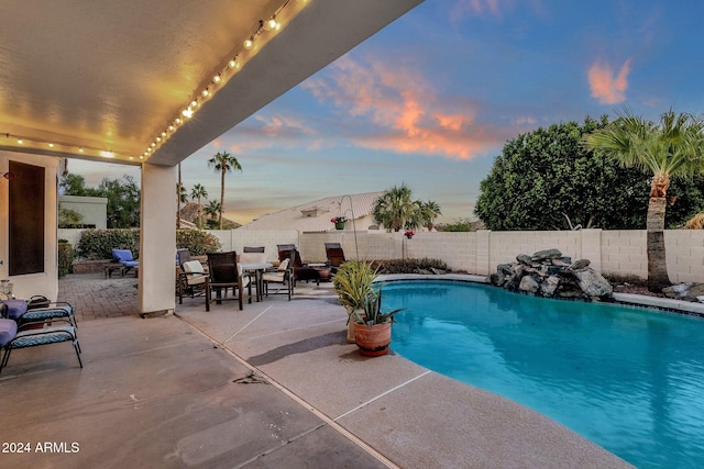 pool at dusk featuring a patio area