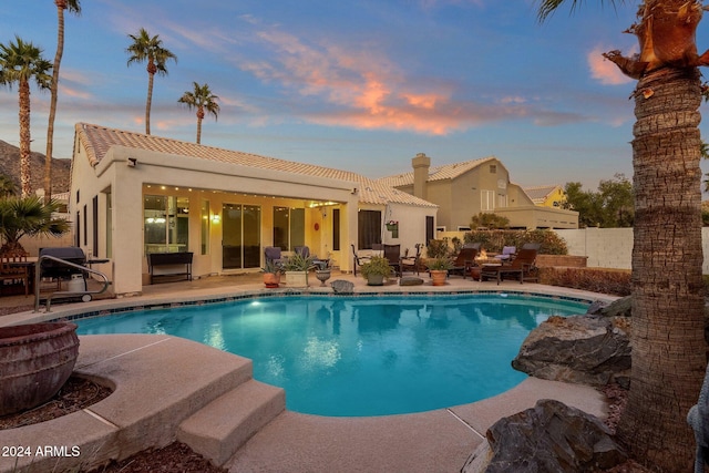 pool at dusk featuring a patio area