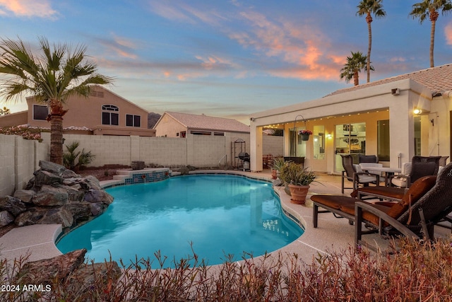 pool at dusk featuring a patio