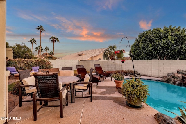 pool at dusk with a patio area