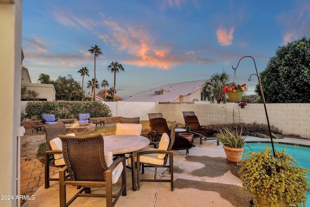 patio terrace at dusk featuring a fenced in pool