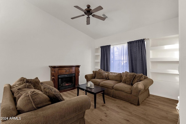 living room with wood-type flooring, built in features, ceiling fan, and lofted ceiling