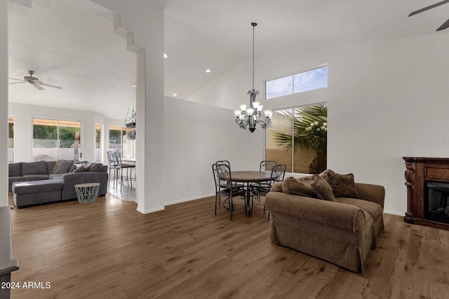 living room with hardwood / wood-style floors, ceiling fan with notable chandelier, and high vaulted ceiling