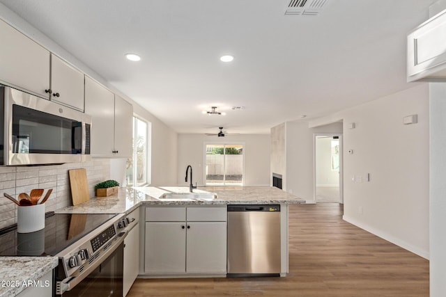 kitchen with ceiling fan, sink, kitchen peninsula, white cabinets, and appliances with stainless steel finishes