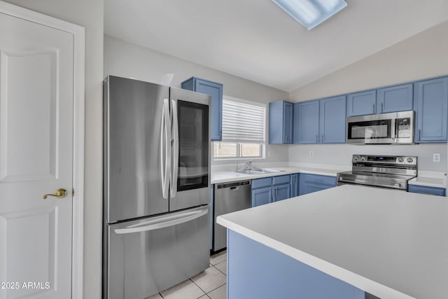 kitchen featuring light countertops, appliances with stainless steel finishes, blue cabinetry, and lofted ceiling