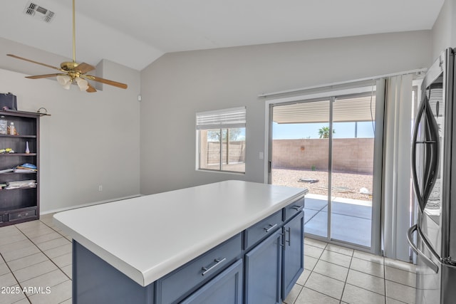 kitchen with light tile patterned flooring, lofted ceiling, visible vents, and stainless steel refrigerator
