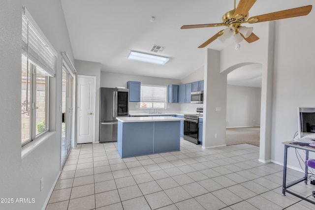 kitchen with arched walkways, blue cabinets, light countertops, lofted ceiling, and stainless steel appliances