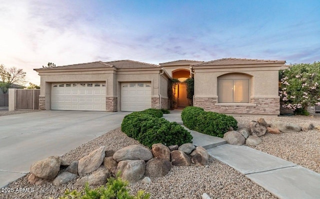 view of front of home with an attached garage, fence, stone siding, driveway, and stucco siding