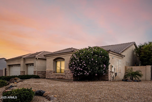 view of front of property featuring an attached garage, stone siding, a tiled roof, and stucco siding