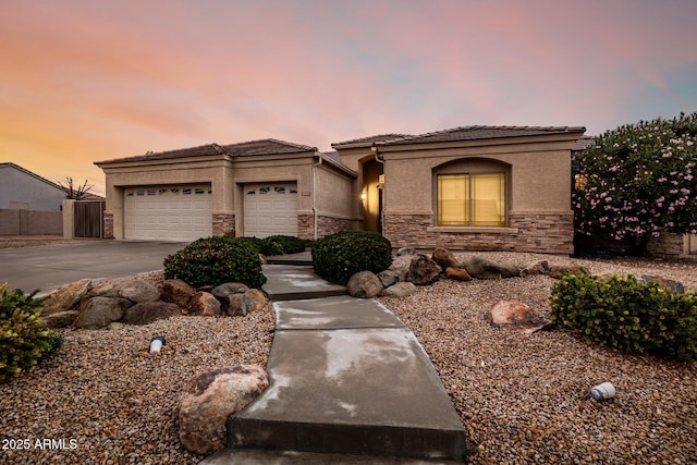 view of front of home with an attached garage, stone siding, concrete driveway, and stucco siding