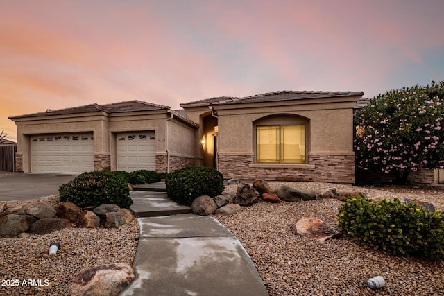 view of front of home with stone siding, driveway, an attached garage, and stucco siding