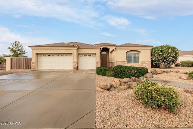 view of front of home with an attached garage, a tile roof, driveway, stone siding, and stucco siding