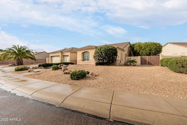 view of front of property with stone siding, an attached garage, a gate, fence, and stucco siding