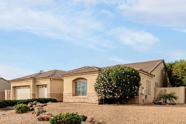 view of front of home featuring stone siding, an attached garage, fence, and stucco siding