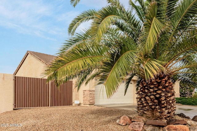 view of home's exterior with a garage, driveway, a gate, and stucco siding