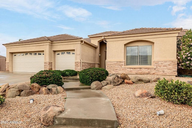 view of front of house featuring a tile roof, stucco siding, concrete driveway, a garage, and stone siding