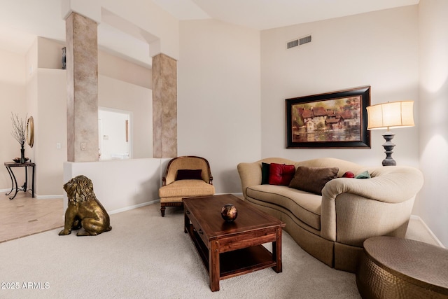 carpeted living room with decorative columns, visible vents, and baseboards