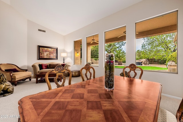 carpeted dining space with lofted ceiling, baseboards, visible vents, and a ceiling fan