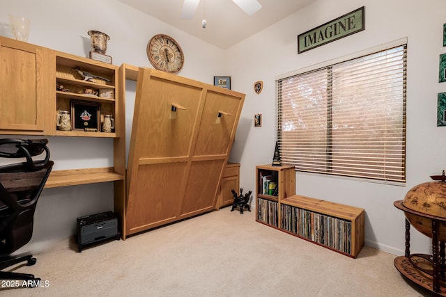 home office with vaulted ceiling, built in desk, a ceiling fan, and light colored carpet