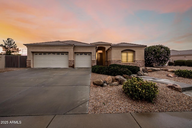 view of front of property featuring a garage, driveway, stone siding, a tile roof, and stucco siding