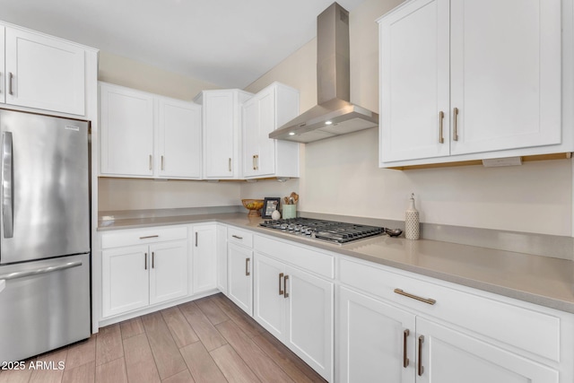 kitchen with wall chimney exhaust hood, white cabinetry, and appliances with stainless steel finishes