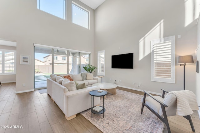 living room with light hardwood / wood-style floors and a high ceiling