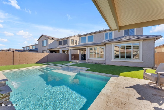 back of house with a swimming pool with hot tub, a patio, and a yard