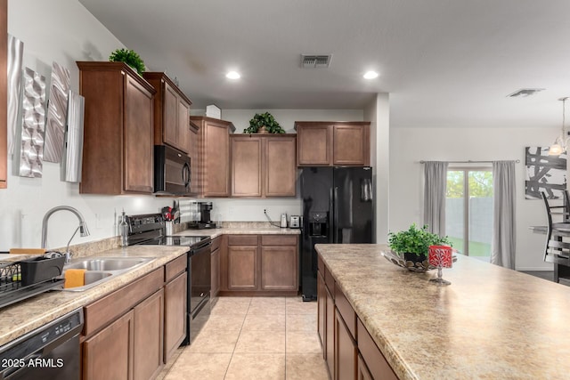 kitchen featuring light tile patterned floors, decorative light fixtures, sink, and black appliances