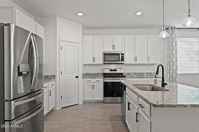 kitchen with hanging light fixtures, appliances with stainless steel finishes, sink, and white cabinets