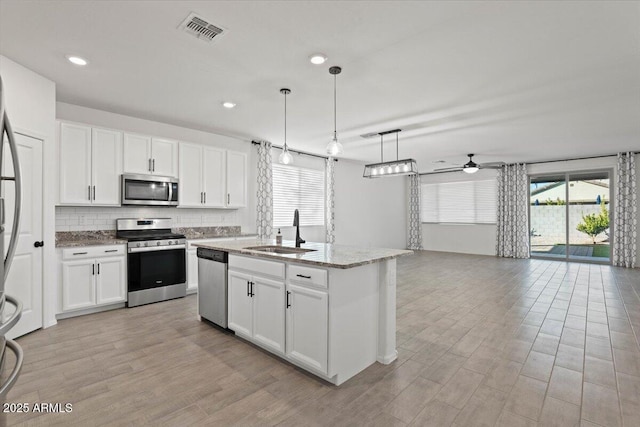 kitchen featuring pendant lighting, stainless steel appliances, sink, and white cabinets