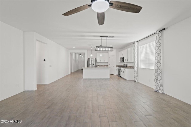 unfurnished living room with ceiling fan and light wood-type flooring