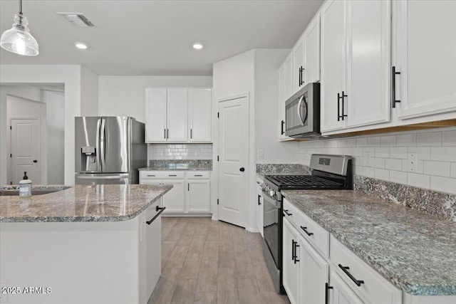 kitchen featuring white cabinetry, appliances with stainless steel finishes, and pendant lighting