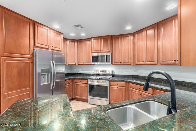 kitchen featuring sink, stainless steel appliances, and dark stone countertops