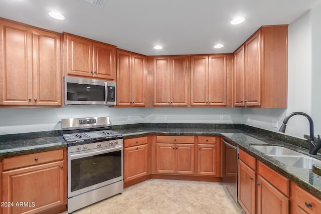 kitchen with sink, stainless steel appliances, and dark stone countertops