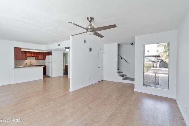 unfurnished living room featuring ceiling fan and light wood-type flooring