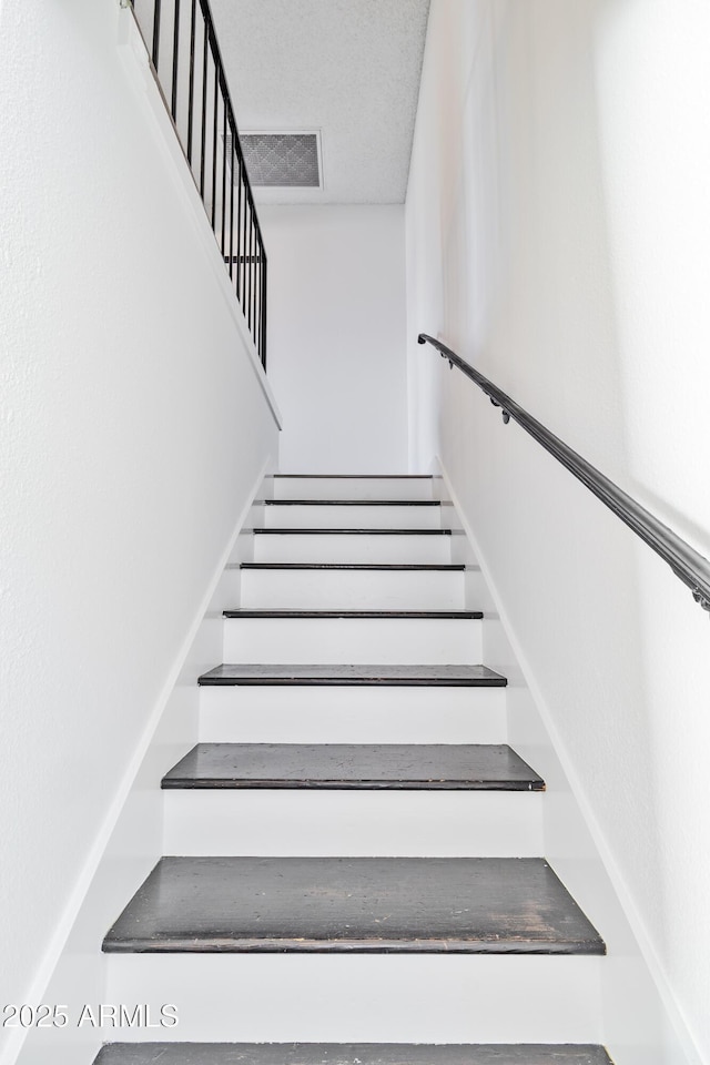 staircase with a textured ceiling