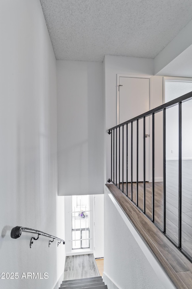 stairs with wood-type flooring and a textured ceiling