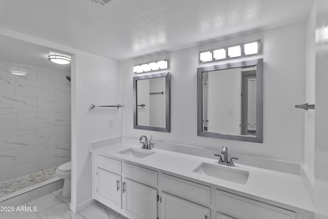 bathroom featuring tiled shower, vanity, toilet, and a textured ceiling