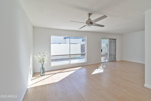 spare room with plenty of natural light, ceiling fan, and light wood-type flooring