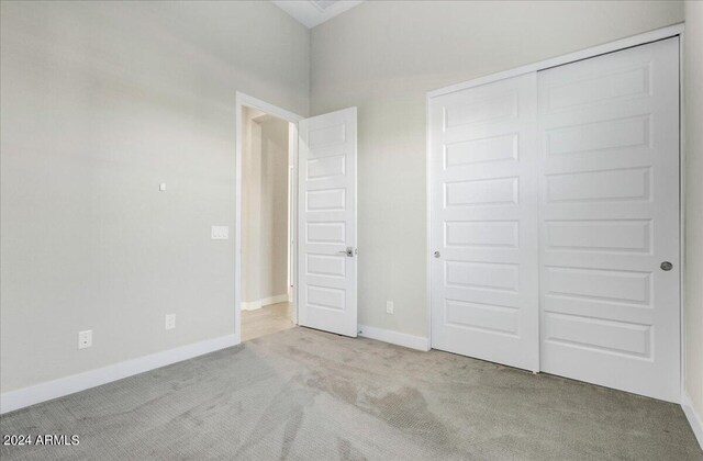 unfurnished bedroom featuring light colored carpet and a closet