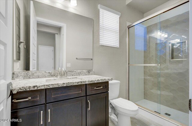 bathroom featuring an enclosed shower, vanity, and toilet