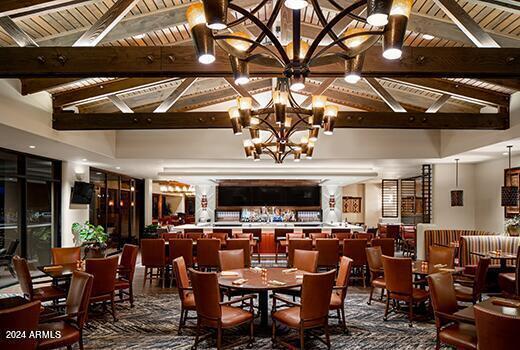 dining area featuring lofted ceiling with beams and a chandelier