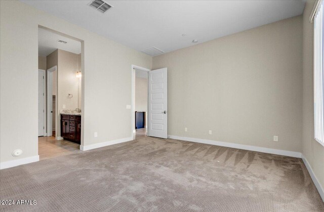 unfurnished bedroom with light carpet and connected bathroom