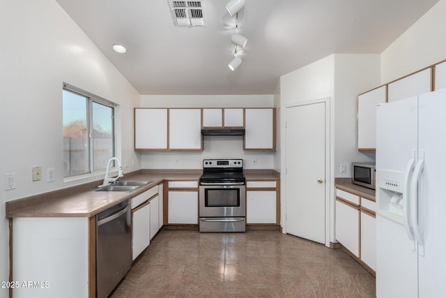 kitchen with appliances with stainless steel finishes, rail lighting, sink, and white cabinets