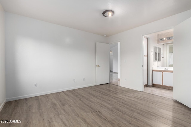 unfurnished bedroom featuring ensuite bathroom and light hardwood / wood-style floors